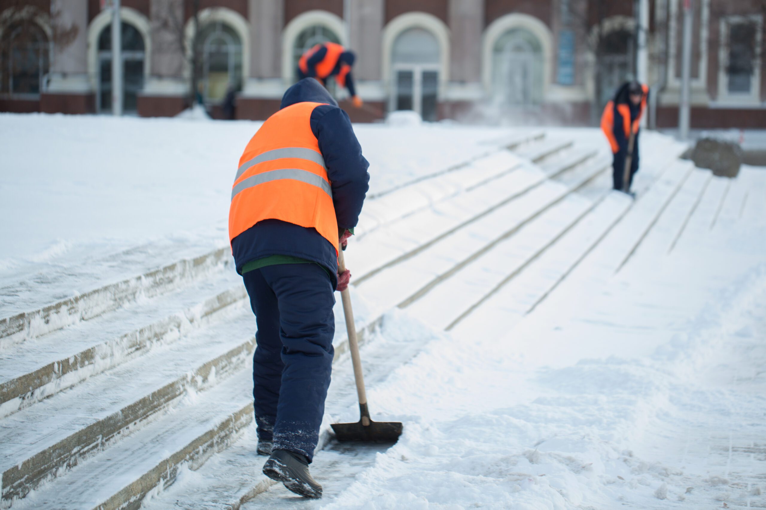 Workers sweep snow from road in winter, Cleaning road from snow storm.